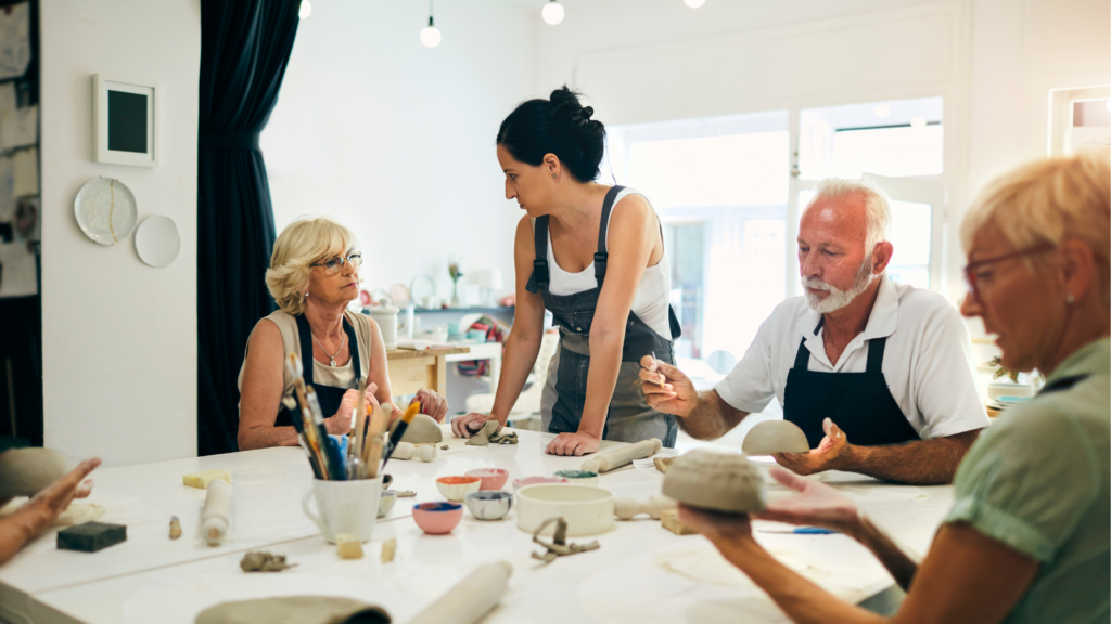un-groupe-de-seniors-en-atelier-décoration-ceramique-avec-une-intervenante