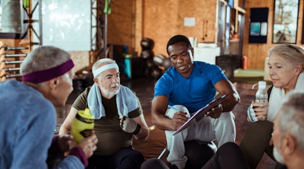 Animateur-présentant-un-programme-de-gym-douce-à-un-groupe-de-seniors-en-cercle-après-la-séance