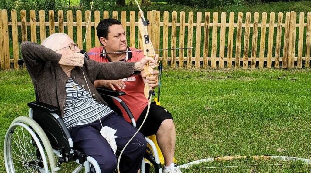 Résident-en-fauteuil-roulant-participant-à-une-activité-de-tir-à-l-arc-adaptée-en-EHPAD-atelier-adaptée