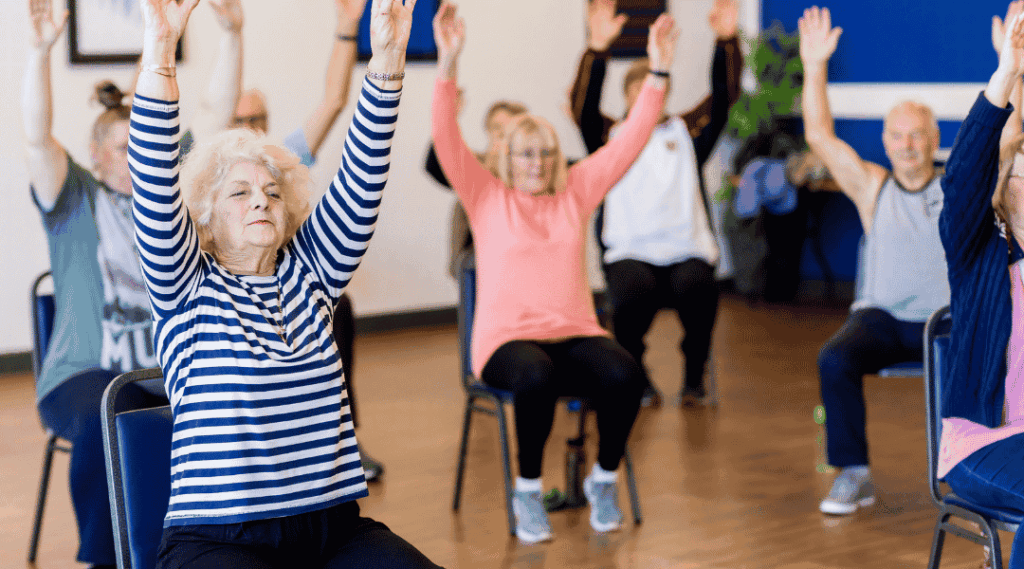 un-groupe-de-seniors-effectue-des-exercices-de-gymnastique-sur-chaise-en-levant-les-bras-en-residence-senior