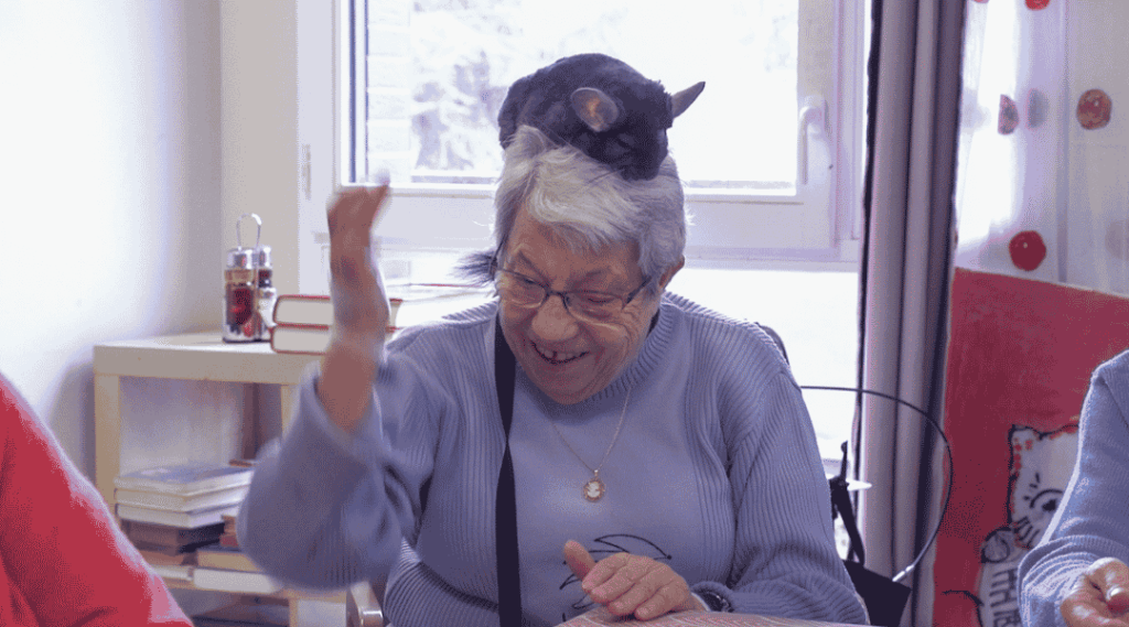 Une-femme-âgée-avec-un-chinchilla-posé-sur-sa-tête-lors-d-une-séance-de-zoothérapie